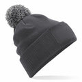 The Beechfield BC443 is a gray knit beanie featuring a pom-pom on top, a ribbed fold-over cuff, and a rectangular patch on the front.