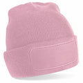 Product BC445 by Beechfield is shown against a white background. This pink knit beanie features a blank rectangular patch on the front, a folded cuff, and a ribbed texture.