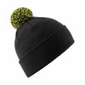 Introducing the BC450 by Beechfield: a stylish black knit beanie featuring a vibrant green and black pom-pom on top. This hat is designed with a folded cuff to enhance both warmth and style.