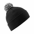 The BC450 by Beechfield is a black knit beanie featuring a white and black pom-pom on top. It includes a folded cuff for a snug and warm fit, ideal for cold weather, and is displayed against a white background.