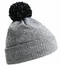 The Beechfield BC450 is a gray knitted beanie featuring a folded brim and a playful black pom-pom on top, with its textured design clearly visible.