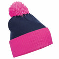 A Beechfield BC451 knit beanie in navy blue, featuring a bright pink cuff and a matching pink pom-pom on top.