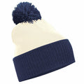 The BC451 beanie by Beechfield is cream-colored with a dark blue fold-over brim and features a matching blue pom-pom on top.