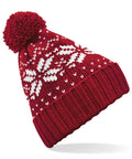 The Beechfield BC456 is a red knitted beanie adorned with a pom-pom on top and white snowflake patterns.