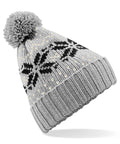The Beechfield BC456 is a gray knitted winter hat adorned with black snowflake patterns and a ribbed brim, complete with a pom-pom on top.