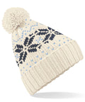 The Beechfield BC456 beanie is a cozy white knitted hat with a prominent pom-pom, featuring an intricate pattern of black and light blue snowflakes. Its ribbed edge enhances its snug appearance.