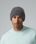 A person wearing a grey Beechfield BC45R beanie and a light blue sweatshirt looks directly at the camera against a plain grey background.