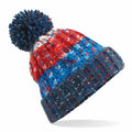 The BC486 by Beechfield is a multicolored beanie with a pom-pom on top, showcasing blue, red, and white patches. It features a textured pattern and a ribbed fold-over edge.