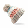 The Beechfield BC486 is a vibrant knitted winter hat adorned with a large pom-pom, showcasing a blend of pastel orange, teal, white, and beige hues. It features ribbing at the bottom and an intricate textured pattern throughout.