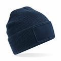 A Beechfield BC540 knit beanie in navy blue featuring a blank rectangular patch on the front.