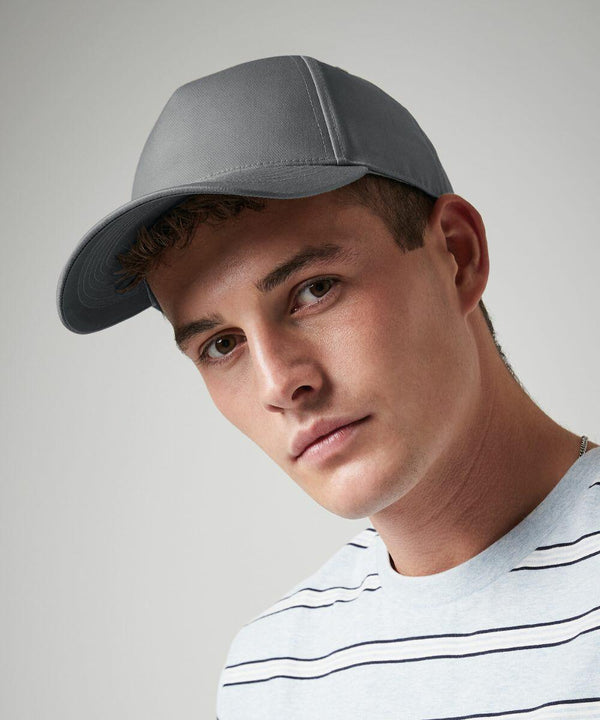 A person wearing a grey Beechfield BC649 baseball cap and a light-colored shirt with thin horizontal stripes looks at the camera. The background is plain grey.