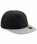 The Beechfield BC660 is a flat-brim snapback cap featuring a black top and gray brim and button. A circular sticker with text and the Beechfield logo is displayed on the brim.