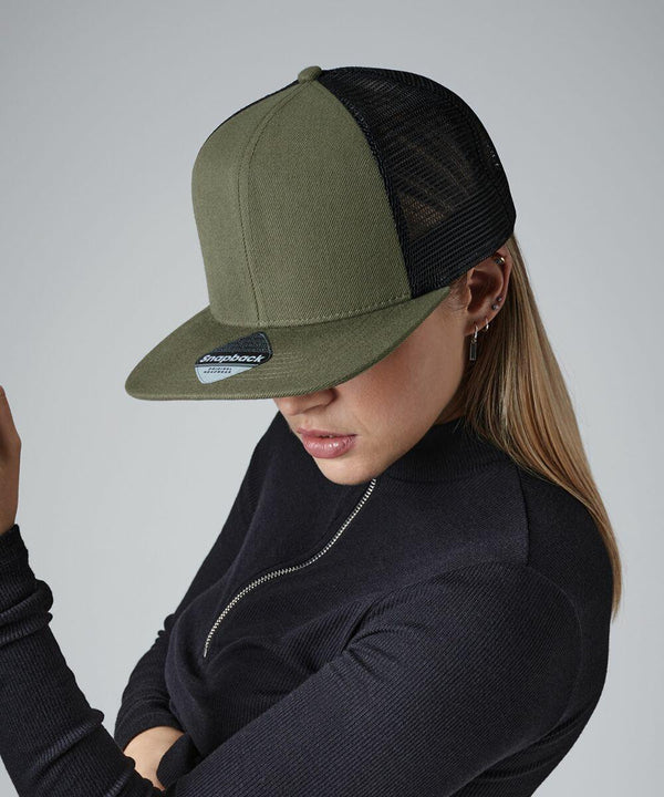 A person wearing a dark olive green Beechfield BC664 trucker cap with a black mesh back, styled with silver hoop earrings and a black zippered top. The individual's head is slightly tilted down, obscuring their face partially from view. The background is plain grey.