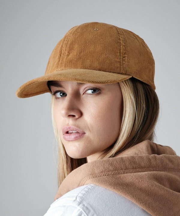 A person with long hair wears a Beechfield BC682 corduroy baseball cap and a matching sweater, looking at the camera with a neutral expression against a plain grey background.