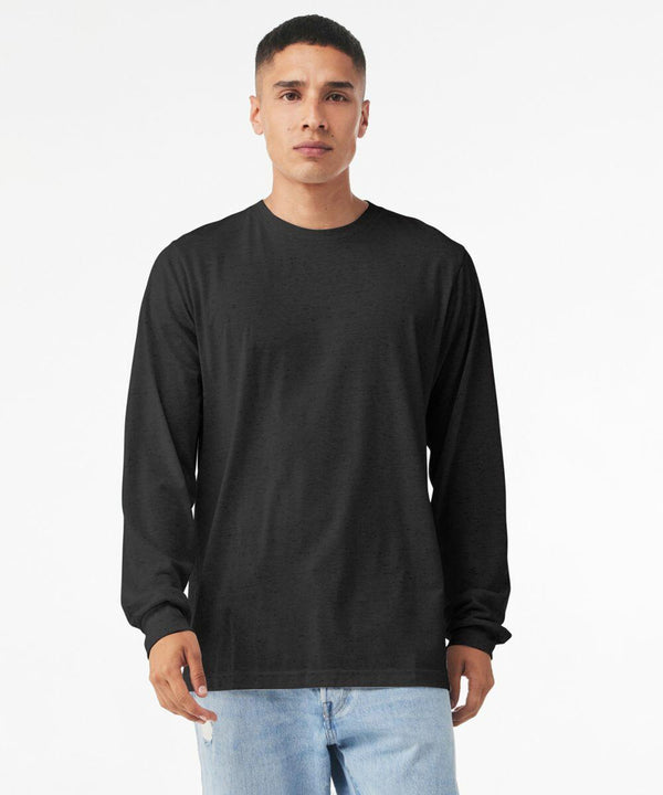 A person with short hair is standing against a plain white background. They are wearing a Bella Canvas BE44H black long-sleeve shirt and light blue jeans. They have a neutral facial expression and their arms are relaxed at their sides.