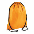 A Bagbase BG005 drawstring backpack in orange, featuring black cords, is displayed. The top of the bag is gathered, and it includes reinforced metal grommets at the bottom corners for the cords.