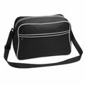 The Bagbase BG014 is a black messenger bag featuring white piping, a front zippered pocket, and an adjustable shoulder strap.