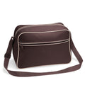 Introducing the BG014 by Bagbase: a brown shoulder bag with white piping, equipped with a long adjustable strap. This stylish bag features a spacious main compartment and an additional front zipper pocket for extra storage. Photographed against a simple white background, it's both functional and fashionable.