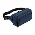 The BG053 by Bagbase is a waist bag in blue, featuring two zippered compartments and an adjustable black strap.
