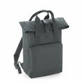 The BG118 from Bagbase is presented standing upright against a white background. This dark green backpack boasts a roll-top design with buckle closure, a front zippered pocket, adjustable shoulder straps, and a top handle.
