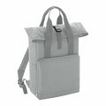 Introducing the BG118 from Bagbase: a light gray backpack featuring a top flap secured by a buckle. It comes equipped with two shoulder straps and a convenient handle for easy carrying. The front boasts a large zipper pocket, embodying simplicity and modernity in its design.