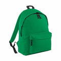 The BG125 backpack from Bagbase is shown in a vibrant green color with black zippers and straps. It features a spacious main compartment and a front zippered pocket, both equipped with black zipper pulls. The backpack is set against a white background.