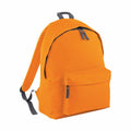 The BG125 by Bagbase is a vibrant orange backpack featuring black zippers and gray straps. It includes a spacious main compartment and a front zip pocket, all designed with simplicity and minimalism in mind.