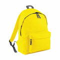 Introducing the BG125 by Bagbase: This vibrant yellow backpack features sleek gray zippers and adjustable shoulder straps. Crafted with a front pocket and a spacious main compartment, it showcases a minimalist and contemporary design against a crisp white backdrop.