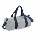 Introducing the Bagbase BG140: a light gray cylindrical duffel bag equipped with navy blue handles and a detachable shoulder strap. It includes a front zipper pocket and has two sturdy main handles for easy carrying, offering a design that is both simple and functional.