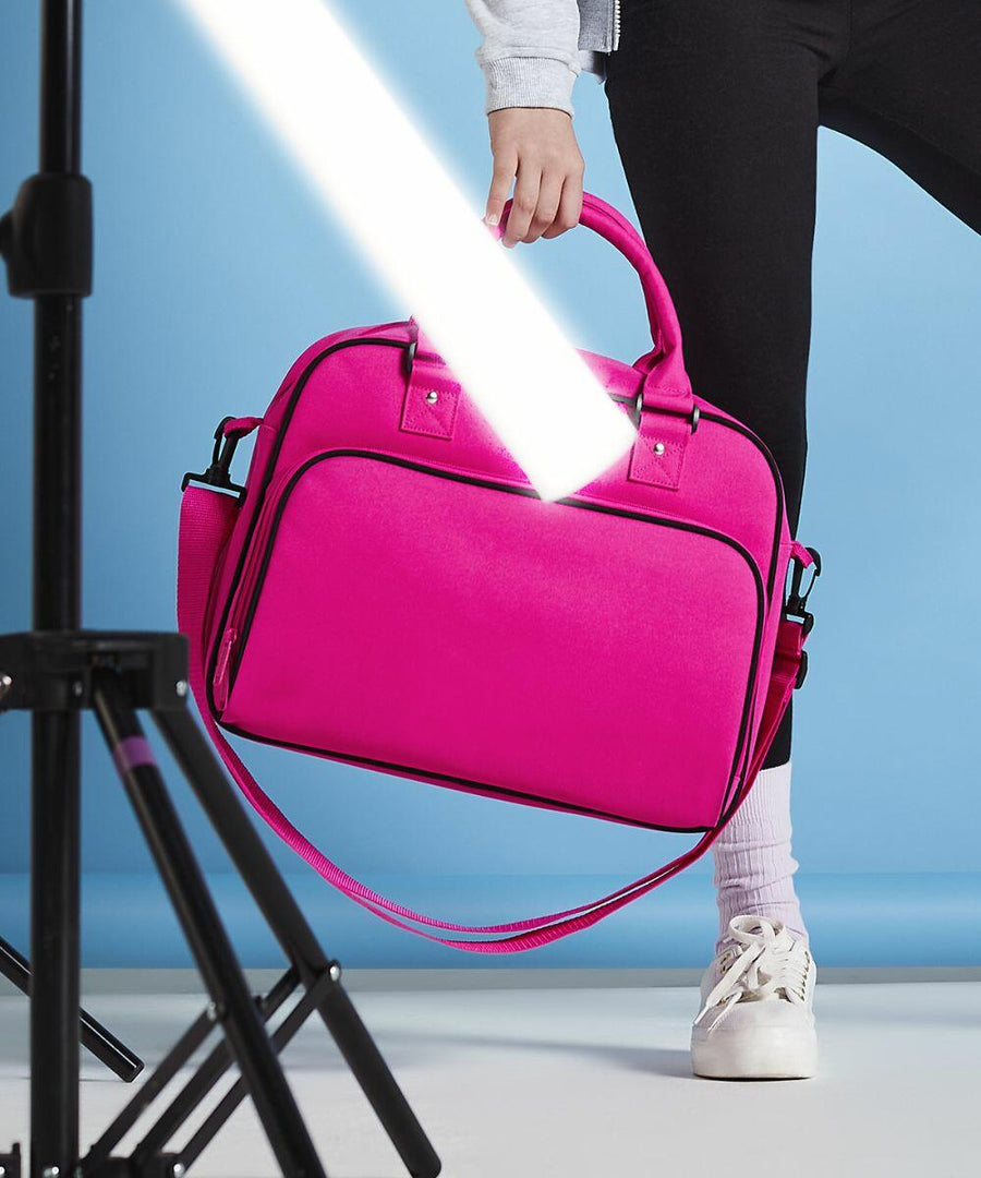 Person holding a Bagbase BG145 by its handles under a studio light against a blue background.