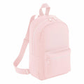 A Bagbase BG153 backpack in light pink, featuring a front zipper pocket, adjustable shoulder straps, and a top handle, displayed on a white background.