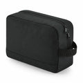 A Bagbase BG277 rectangular toiletry bag in black, featuring a zipper closure and a side handle, positioned at an angle.
