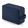 The Bagbase BG277, a dark blue rectangular toiletry bag featuring a zipper and side handle, is displayed against a white background.
