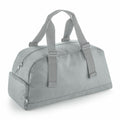 The Bagbase BG278 is a light gray duffel bag featuring dual handles and a zippered closure. It includes zippered side compartments and an adjustable shoulder strap, while its sleek design offers a simple and functional appearance.