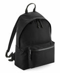 The Bagbase BG285, a black backpack featuring a zippered front pocket and adjustable straps, is displayed on a white background.