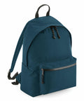 Introducing the BG285 by Bagbase: a sleek dark teal backpack featuring a front zippered pocket, adjustable shoulder straps, and a minimalist design. It also includes a convenient top handle for easy carrying.