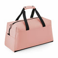 A Bagbase BG338 pink duffel bag featuring black handles and a zippered top.
