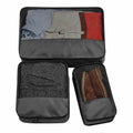 Three black BG459 packing cubes from Bagbase, each containing neatly folded clothes, displayed on a white background.