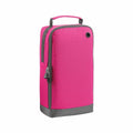 Introducing the Bagbase BG540: a stylish fabric bag featuring a pink body, complemented by a black zipper and a gray bottom. It comes with a convenient small handle on top, alongside a side pocket. Additionally, it includes a grommet hole located near the top corner for added functionality.