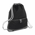The Bagbase BG542 is a black drawstring backpack with gray trim and white drawstrings, featuring a front zippered pocket and two metal grommets at the bottom.