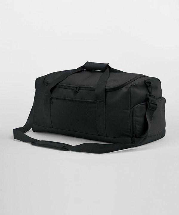 A large black Bagbase BG561 with a front zipper pocket, two handles, and a detachable shoulder strap is displayed on a plain white background. The bag appears to be made from a durable fabric material.