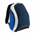 The BG571 backpack by Bagbase is available in a blue and white color scheme with black accents. It features multiple compartments, including a large main section and a front pocket with zippers. The design is simple and sporty, complemented by adjustable shoulder straps.