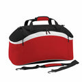 Introducing the Bagbase BG572, a stylish red and black duffel bag accented with a sleek white stripe. It features a top handle, an adjustable shoulder strap, and a zippered main compartment made of sturdy material.