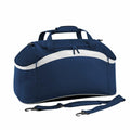 Introducing the Bagbase BG572: a stylish blue duffel bag adorned with a distinctive white curved stripe. This versatile bag features a top handle and an adjustable, detachable shoulder strap. The design includes a convenient main zippered compartment, all showcased against a plain white background.