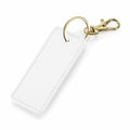 The BG744 by Bagbase is a rectangular white keychain featuring a gold-colored circular ring and lobster clasp. It has a textured finish and offers ample space for customization.