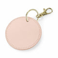 A round, light pink Bagbase BG745 keychain with a textured finish is attached to a gold ring and clasp.