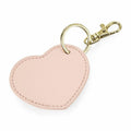Introducing the Bagbase BG746: a heart-shaped keychain crafted with light pink fabric, featuring luxurious gold-tone metal accents such as a keyring and a lobster claw clasp.