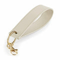 Introducing the BG747 by Bagbase: a beige leather keychain featuring a wrist strap and gold-tone hardware, including a swivel clasp and a keyring. The strap is meticulously stitched, offering a sleek and elegant look.