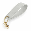 Introducing the Bagbase BG747, a keychain adorned with a thick, textured light gray leather loop. It comes complete with a gold metal ring and a lobster clasp for easy attachment.