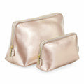 Displayed against a white background, two Bagbase metallic gold cosmetic bags, model BG751, feature zippers and are arranged with the larger bag behind the smaller one. Both bags showcase a shiny, textured surface.